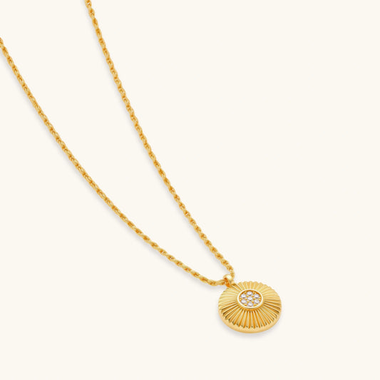 Gold-plated sterling silver necklace with sunburst pendant featuring radiating lines and cubic zirconia center stones