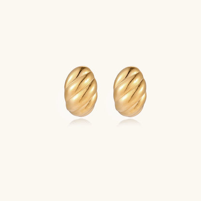 Chunky gold twisted rope huggie hoops with diagonal grooves and high-polish finish on cream background