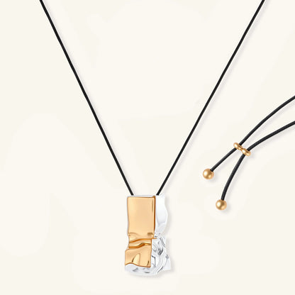 Abstract sculptural pendant necklace with gold and silver toned eco-zinc alloy on black adjustable cord with brass bead details