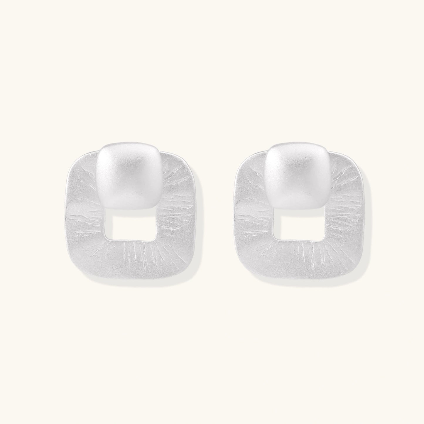 Pair of geometric sterling silver earrings with frosted square frames and glossy rounded studs on white background