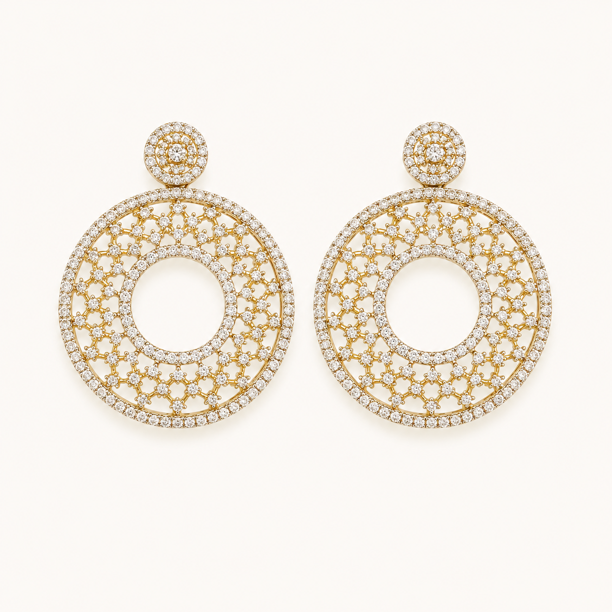 A pair of large gold-tone dangle earrings paved with clear stones, featuring a circular openwork design and a small round stud at the top, shown on a plain off-white background.