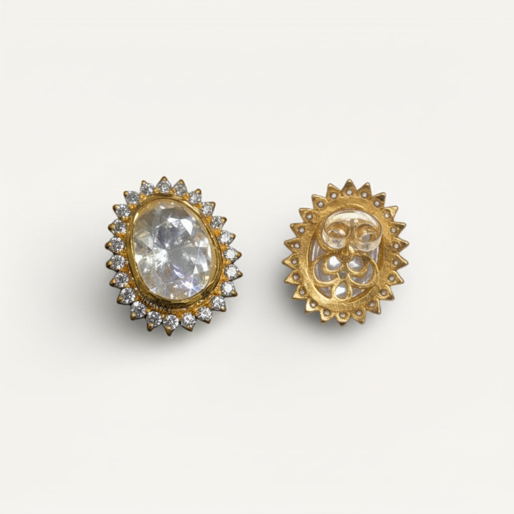 Gold earrings with a central gemstone on a white background