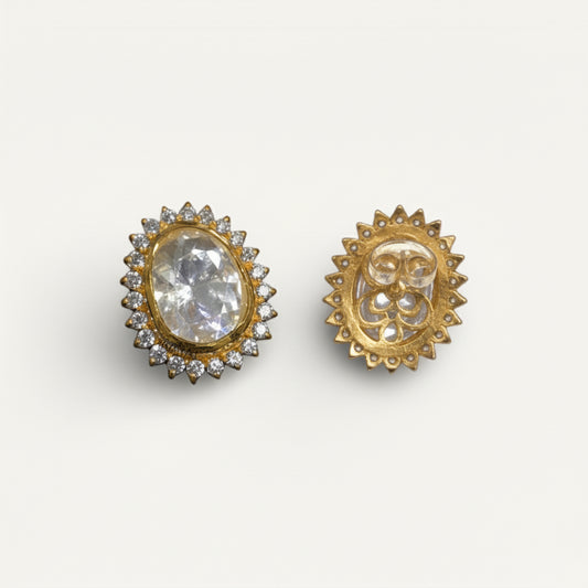 Gold earrings with a central gemstone on a white background