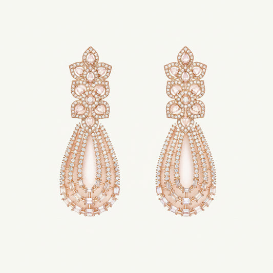 A pair of rose gold statement drop earrings featuring a floral cluster top set with clear stones and a teardrop-shaped lower section with layered clear and pale pink stones, shown on a light cream background.