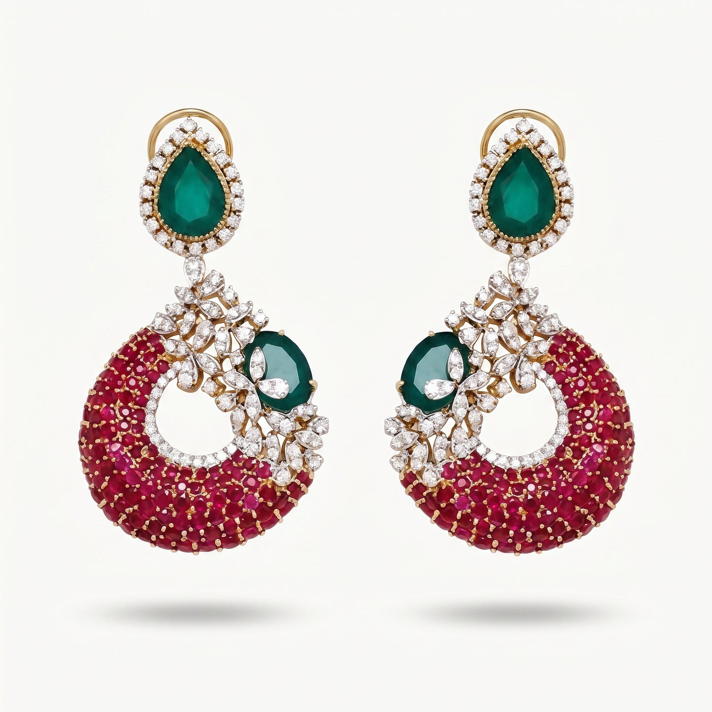 A pair of gold-plated drop earrings featuring a large teardrop-shaped green emerald stone at the top, surrounded by small clear stones, and a crescent-shaped lower section covered in deep pinkish-red stones with a smaller green emerald and clear stone detail.