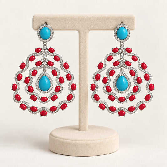 Turquoise and coral chandelier earrings on a cream display stand