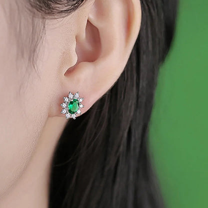 Emerald oval halo stud earring worn on the ear