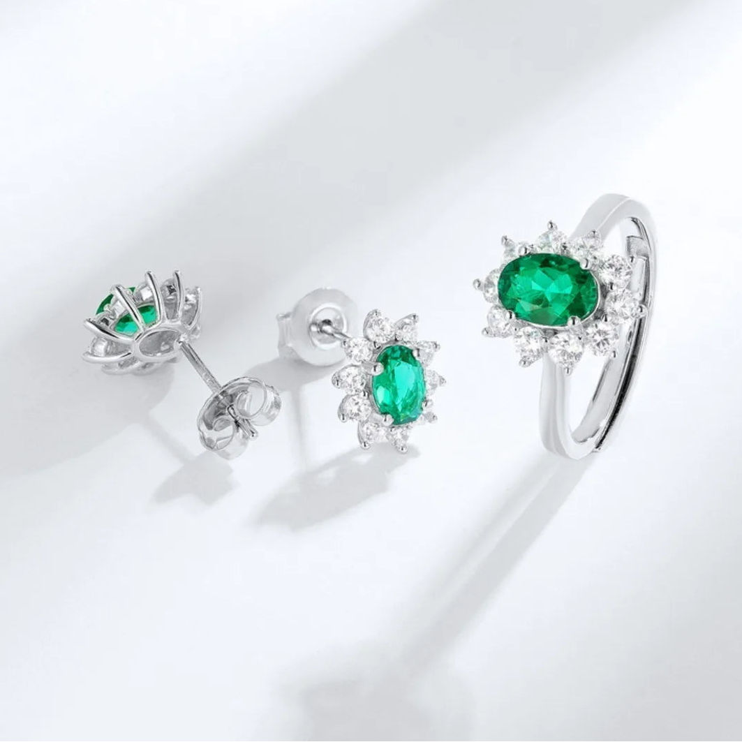 Emerald oval halo earrings beside a coordinating ring; earrings only