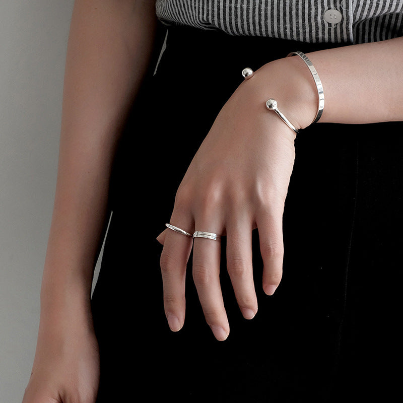 Bead End Open Bangle in 925 sterling silver. A slim adjustable band meets two polished bead ends.
