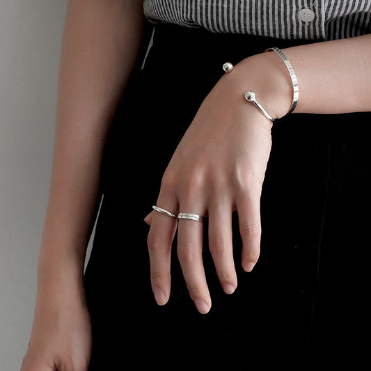 Bead End Open Bangle in 925 sterling silver. A slim adjustable band meets two polished bead ends.