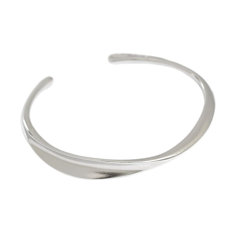 Twisted Curve Open Bangle in 925 sterling silver. A broad polished band turns into a fluid, sculptural twist.