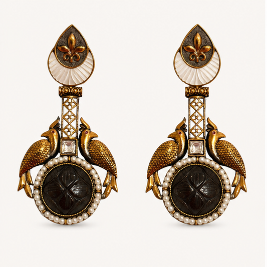 Pair of ornate earrings with gold, black, and pearl details on a white background
