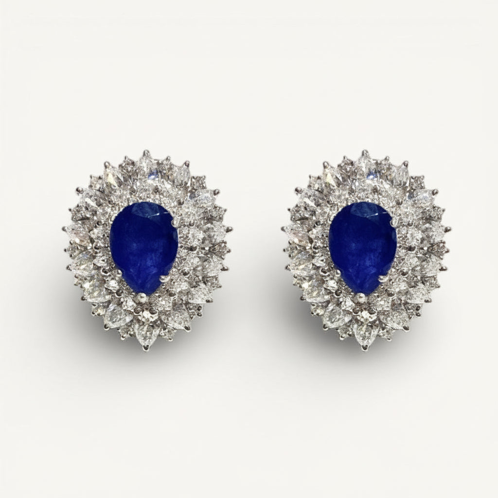 Pair of earrings with blue gemstones and diamond-like stones on a white background