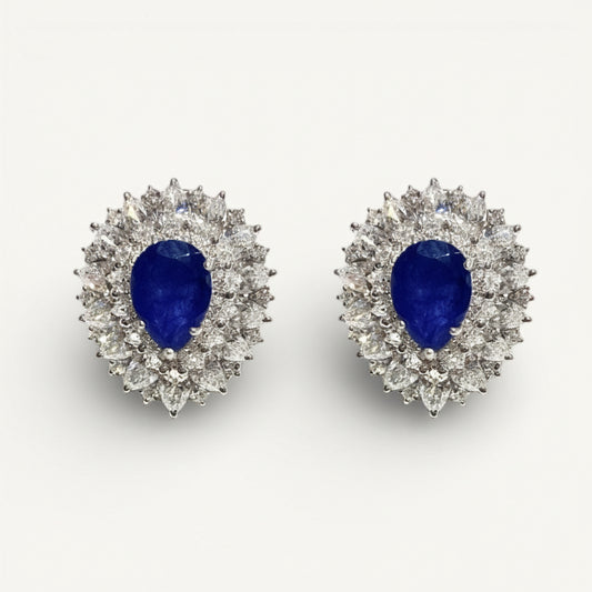 Pair of earrings with blue gemstones and diamond-like stones on a white background